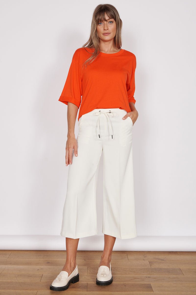 Cream solid midrise cropped trousers has drawstring closure 2 pockets  and buttoned detail along the hem